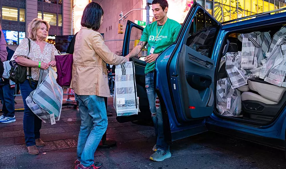 Covenant House Volunteer and donor at Times Square with essential kits for homeless youth | Youth Homelessness Awareness Month