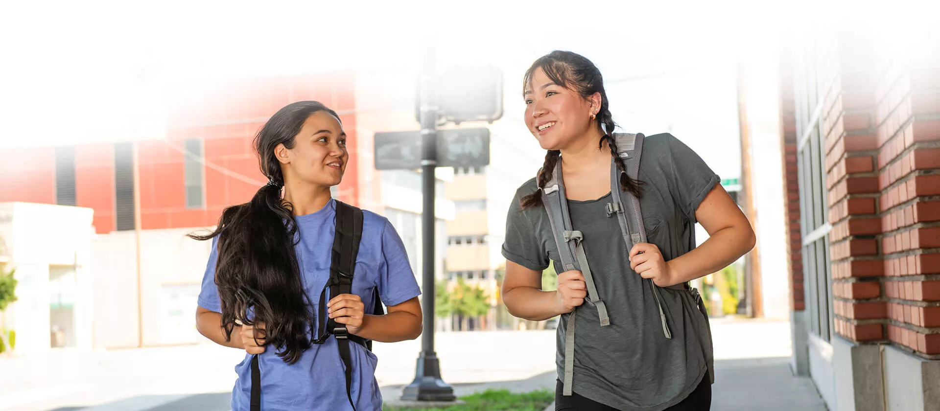 Two young ladies with backpacks walking and talking.