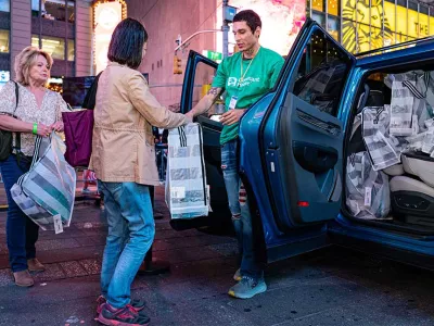 Covenant House Volunteer and donor at Times Square with essential kits for homeless youth | Youth Homelessness Awareness Month