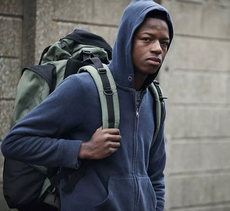 Homeless teen wearing hoodie and backpack | Covenant House - Youth Homelessness Awareness Month